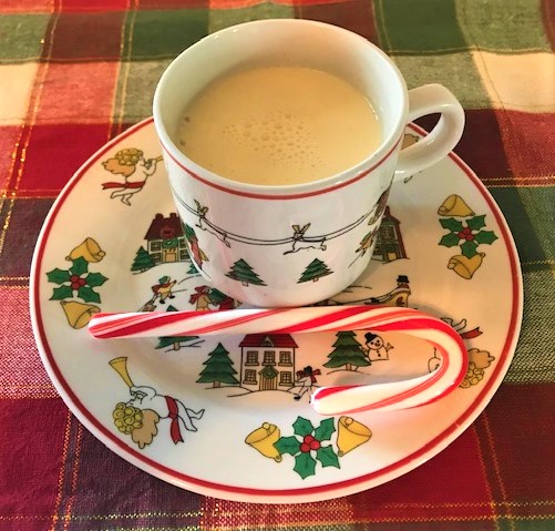 Cup of Eggnog in holiday cup and plate with candy cane adornment