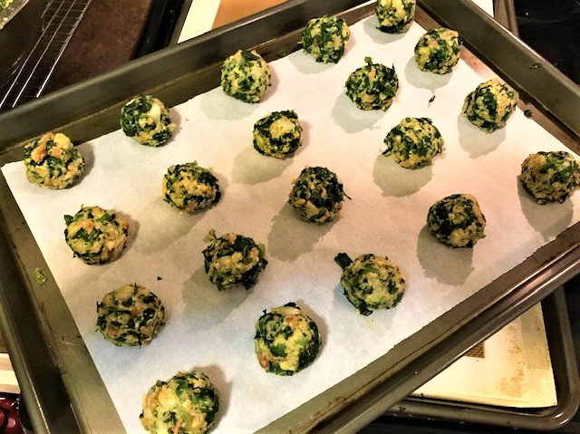 Spinach balls prepared and on baking sheet - ready for oven or freezer.