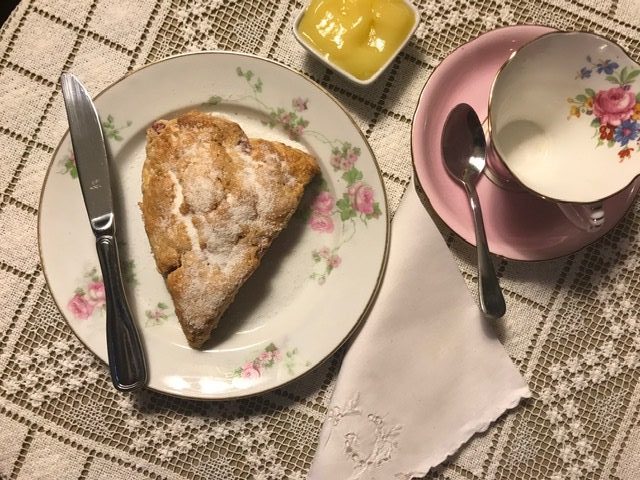 Strawberry Cream Scones plated, with lemon curd and teacup ready to be enjoyed.
