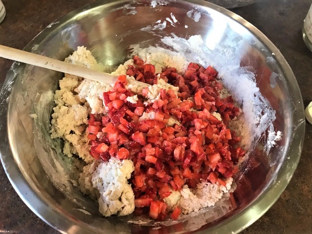 Dough and chopped strawberries combined in mixing bowl