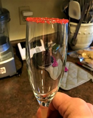 Champagne glass tipped with red crystal sugar.