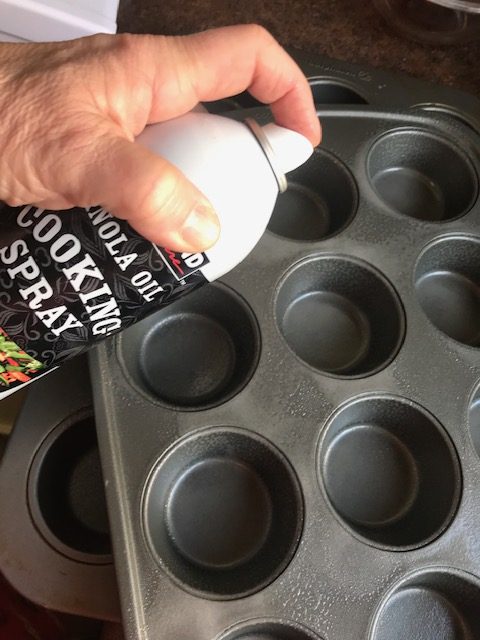 Spraying the muffin tins with cooking spray for the Cheesy Thyme and Ham Potato Gratin Stacks