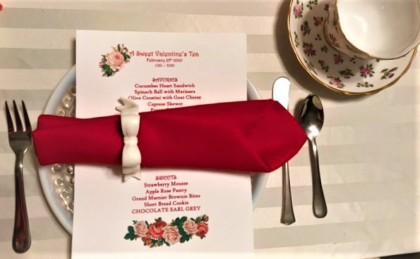 Individual place setting for Valentine Tea Party. Includes cup, silverware, plate, napkin and menu.