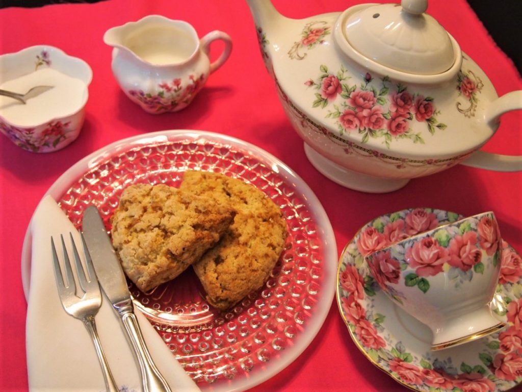 Toffee Scones ready to be served with teapot, teacup, cream and sugar.

